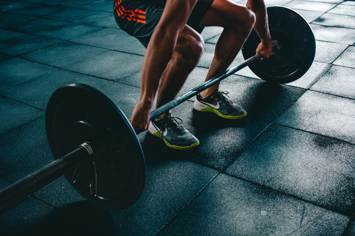 Athlete gripping barbell in dark gym