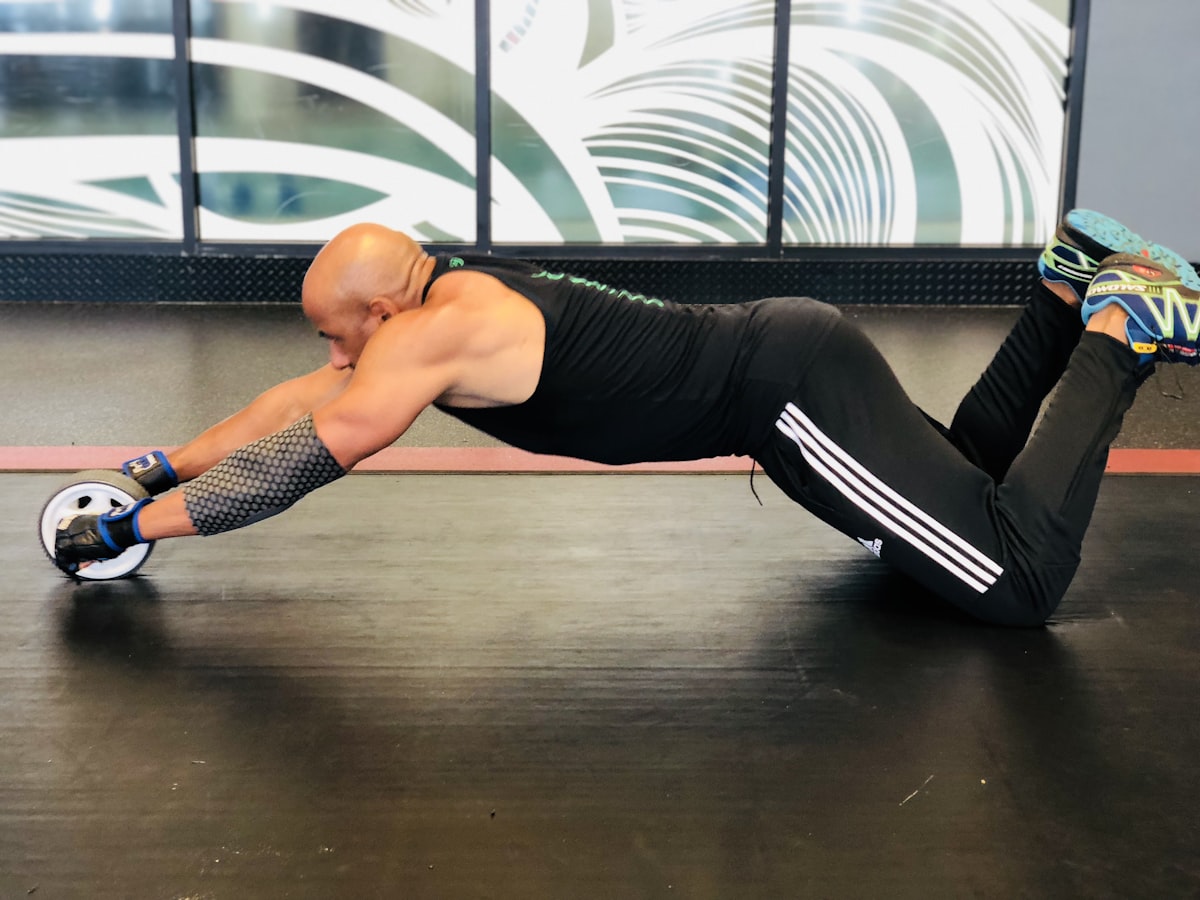Athlete training core with a roller on the gym floor